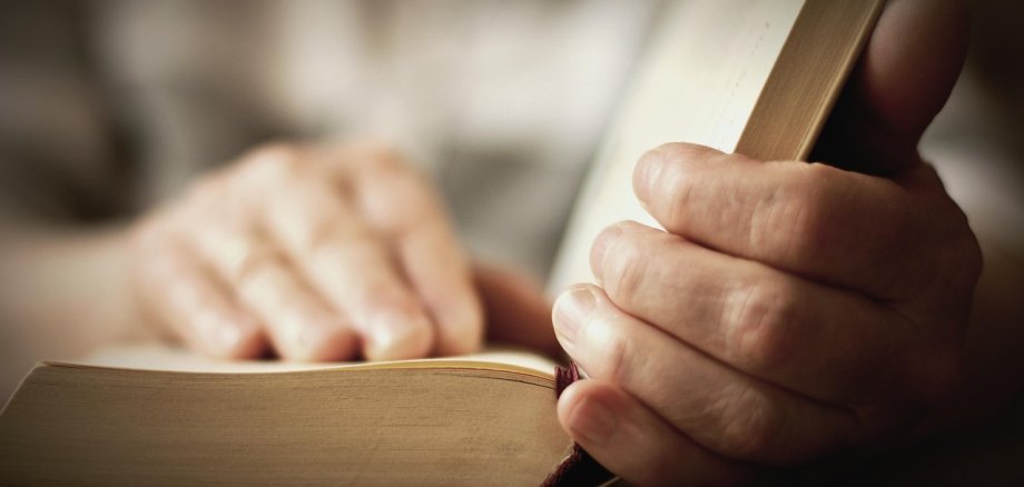 eine Person mit ein Buch liest aber nur die Hände zu sehen sind