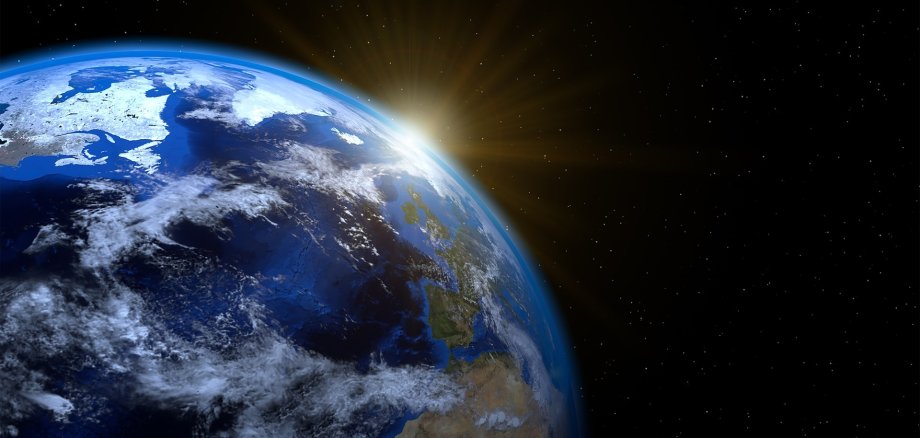 Weltkugel hinten dran die Sonne leicht zu sehen durch Sonnenstrahlen