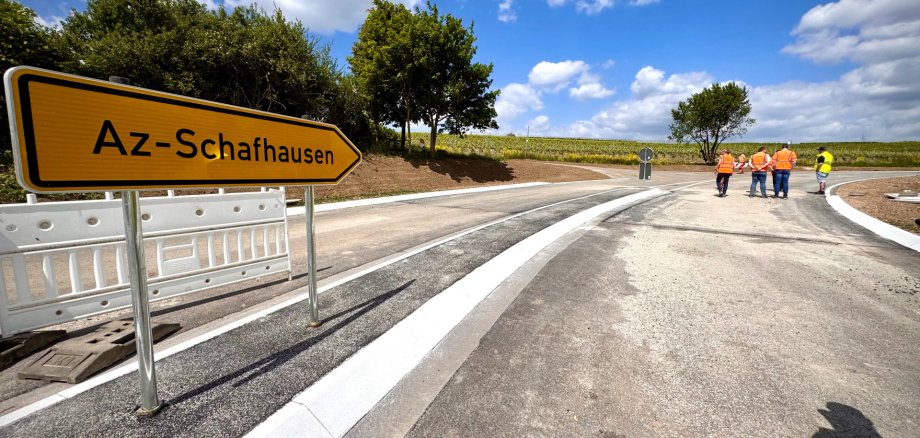 eine neu gebaute Straße mit Arbeitern und einem Schild Richtung Alzey-Schafhausen