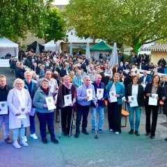 viele Personen im Hintergrund am sitzen/stehen/laufen und vorne eine Gruppe die weißes Blatt von Stadt Alzey halten