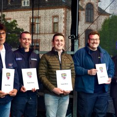 5 Männer stehen und 4 von denen halten ein weißes Papier von der Stadt Alzey