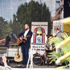 ein Mann singt und spielt eine Holzgitarre auf der Bühne