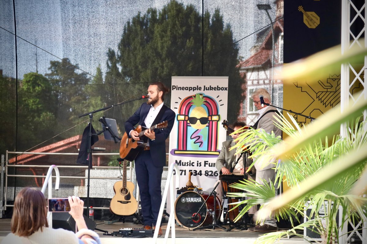 ein Mann singt und spielt eine Holzgitarre auf der Bühne