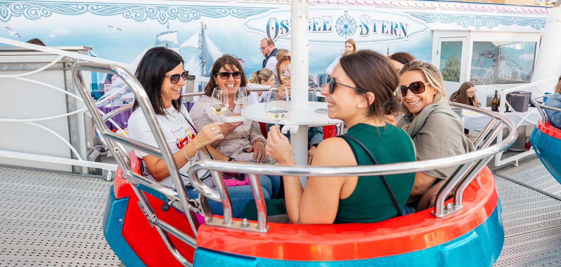 6 Frauen sitzen in einer Gondel mit Wein/-glas in der Hand