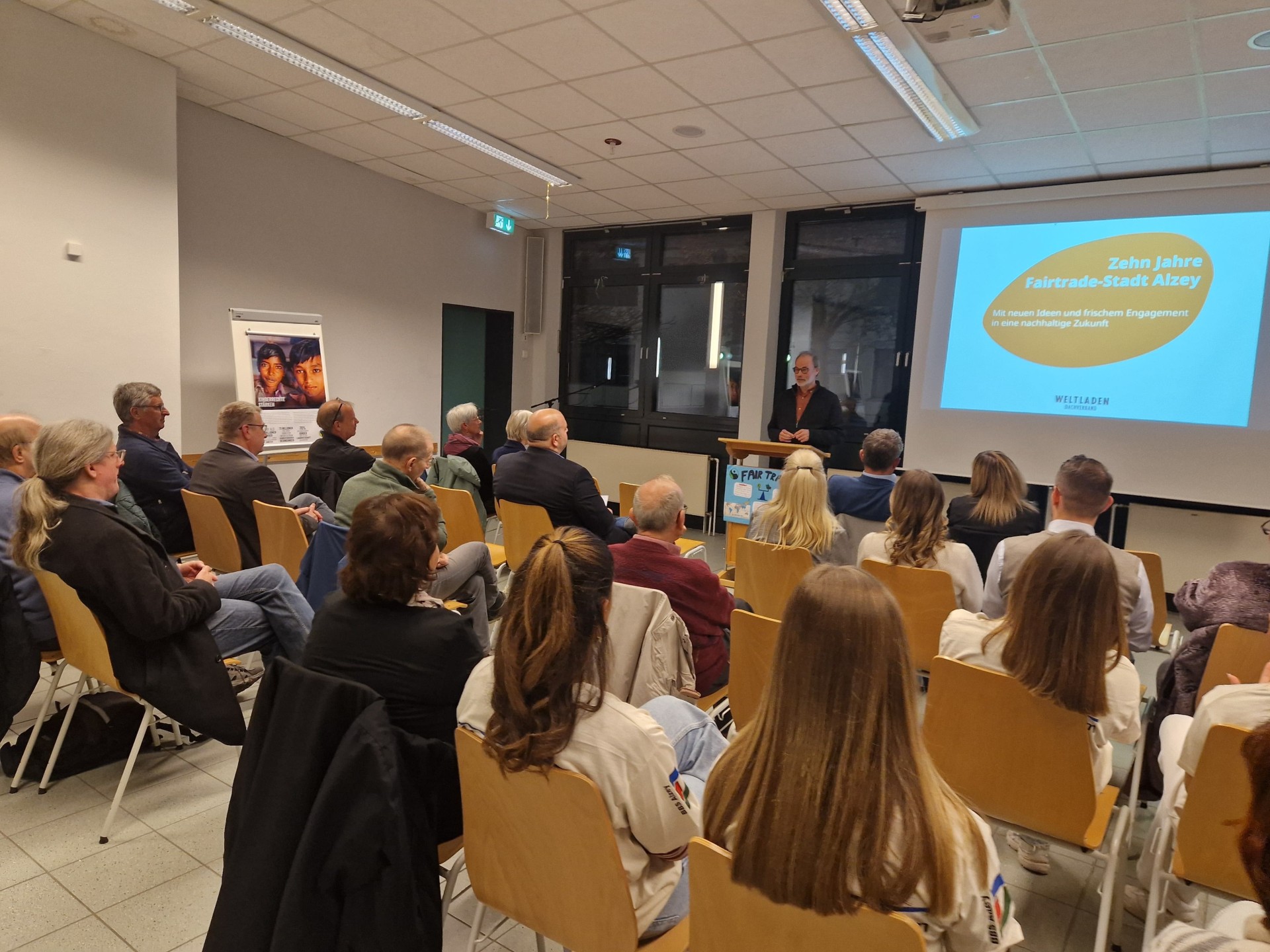 mehrere Personen sitzen in einem Raum und hören einem Vortrag zu