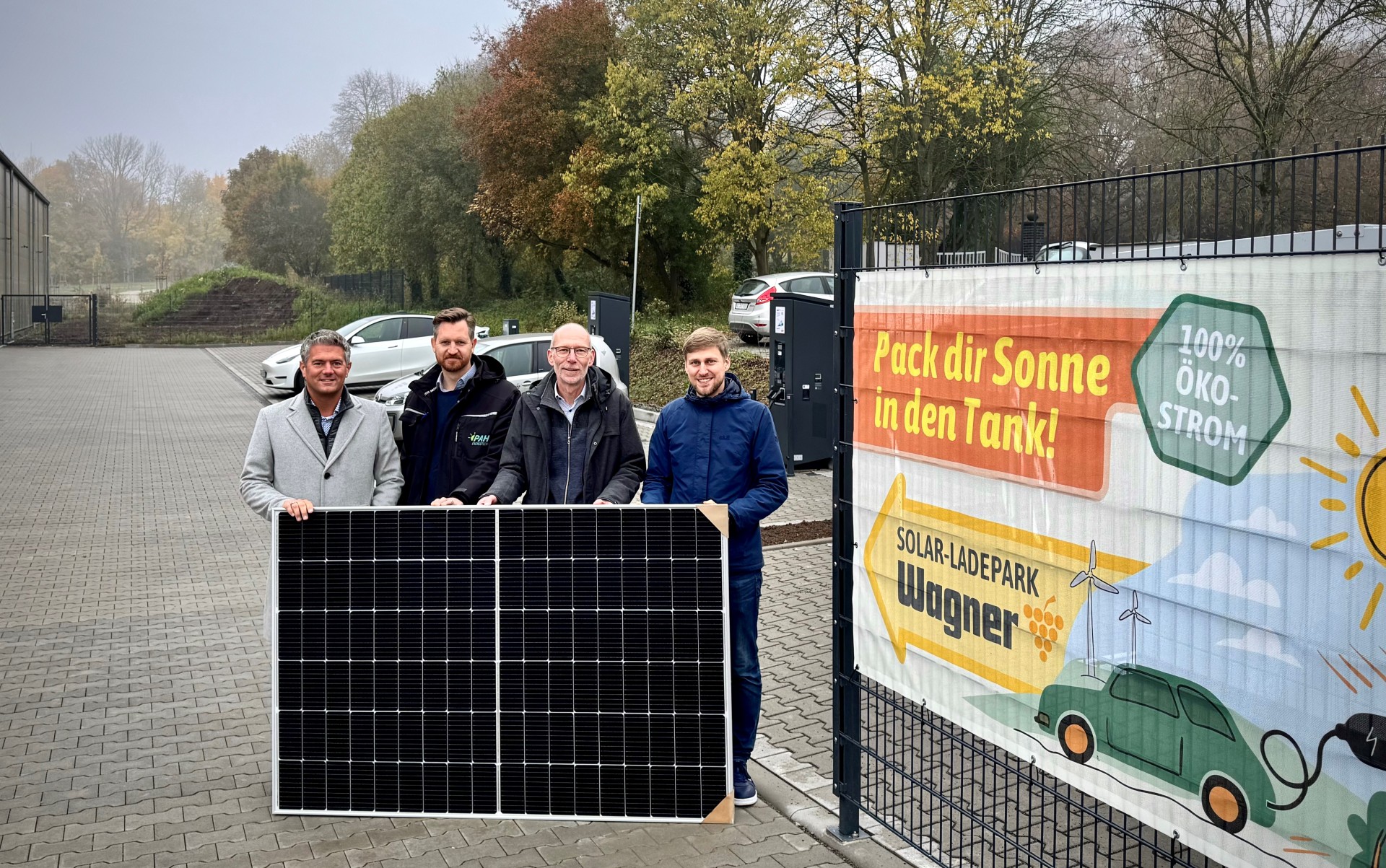 vier Personen halten zusammen ein Photovoltaik Paneel fest.