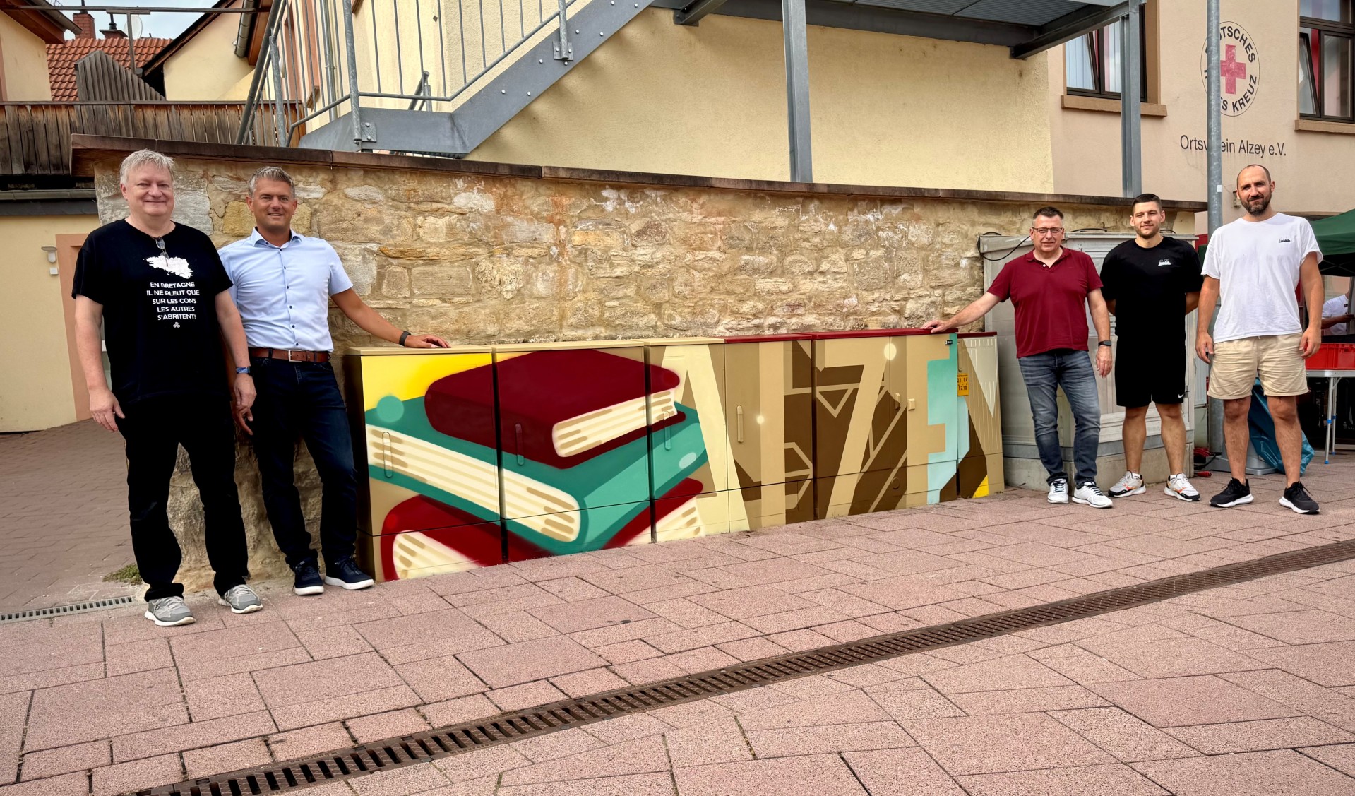 Stromkästen die bunt angemalt wurden in der Stadt Alzey und fünf Männer daneben, einer davon Bürgermeister Steffen Jung