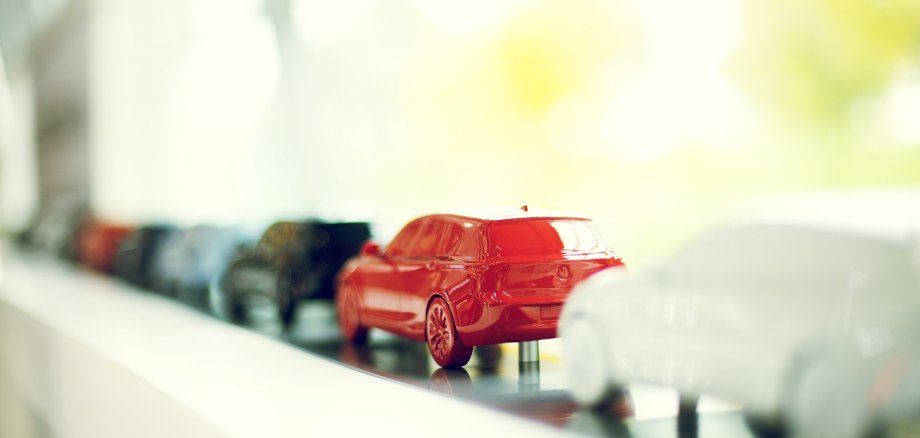 Eine Aufstellung von kleinen Modellautos in einer Reihe, in den Farben weiß, rot und schwarz.