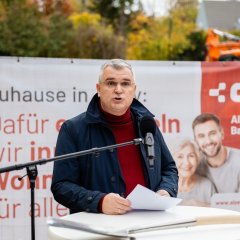 Eine Person hält auf der Baustelle des ehemaligen Stadtgärtnerei-Geländes eine Rede.