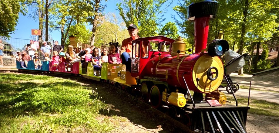 Der rote Alzeyer Volker-Express, fährt mit einigen Kindern über die Schienen auf dem Robinson Spielplatz.