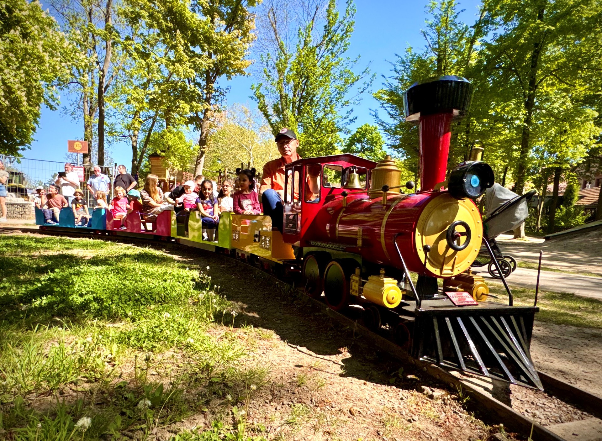 Der rote Alzeyer Volker-Express, fährt mit einigen Kindern über die Schienen auf dem Robinson Spielplatz.