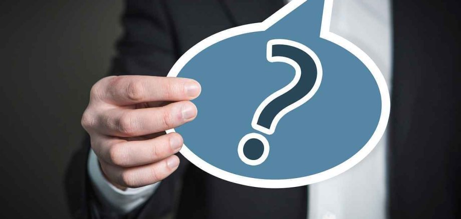 eine blaue Sprechblase mit einem Fragezeichen drin und wird gehalten