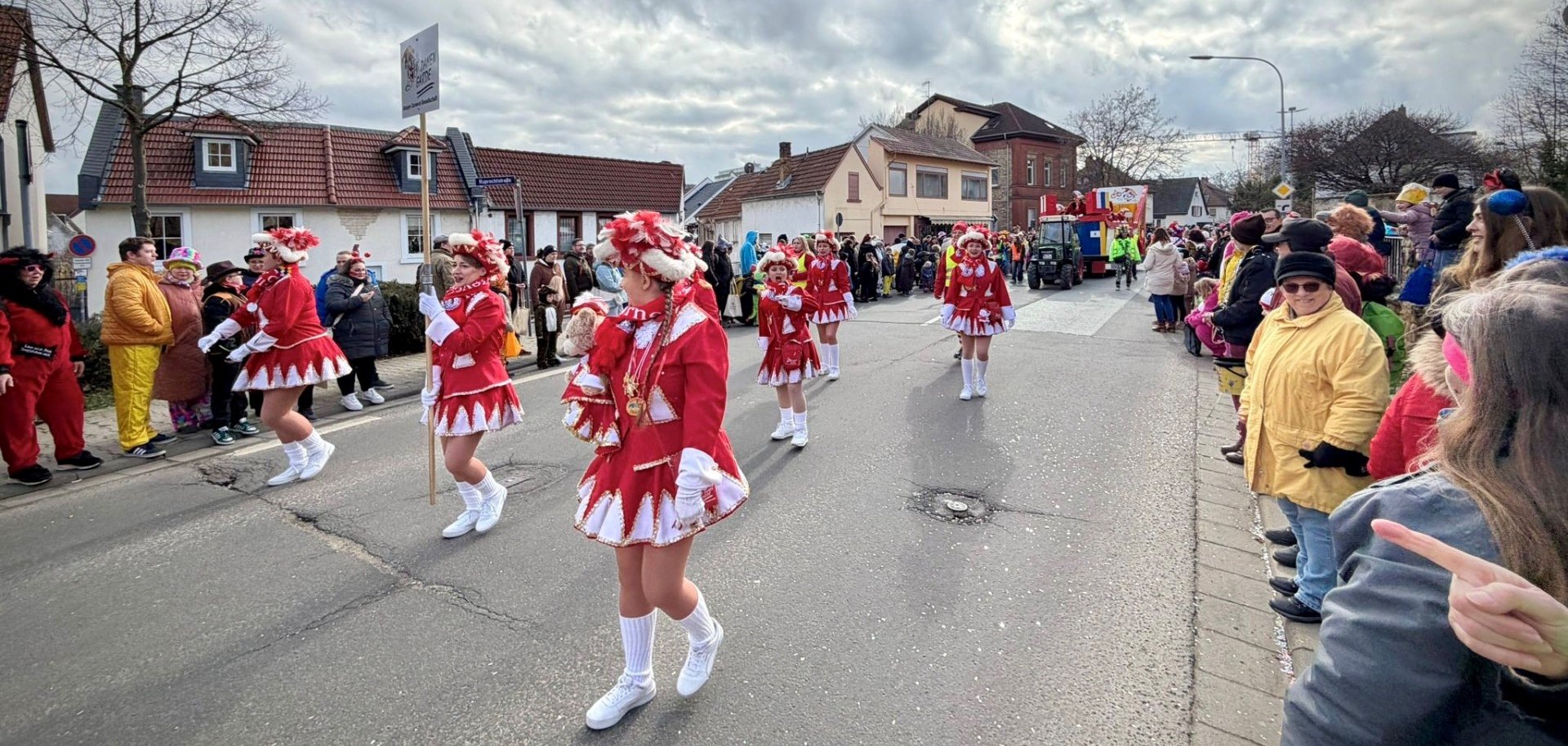 Die  Alzeyer Carneval-Gesellschaft e.V. verkleidet in Rot-Weißen Kostümen gefolgt von ihrem Umzugswagen.