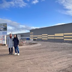 Man sieht die Baustelle des neuen TST-Logistikzentrum von außen und Bürgermeister Steffen Jung der in die Kamera lächelt.