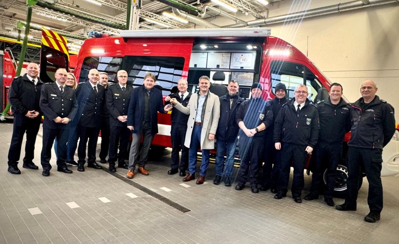 Man sieht die Menschen der Freiwillige Feuerwehr Alzey vor Ihrem neuen Einsatzleitwagen stehen.