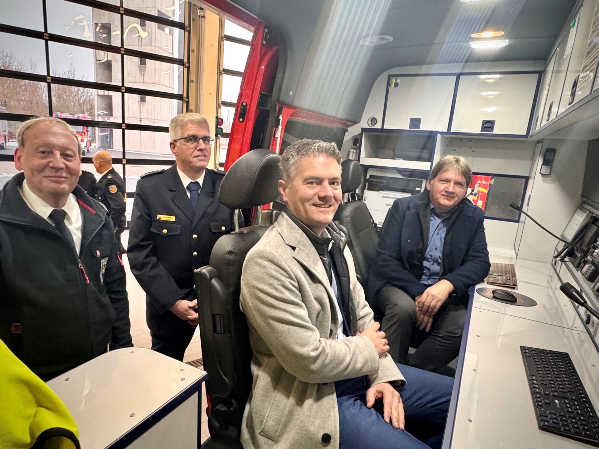 Man sieht einige Menschen der Freiwillige Feuerwehr Alzey die in Ihrem neuen Einsatzleitwagen sitzen und in die Kamera schauen.