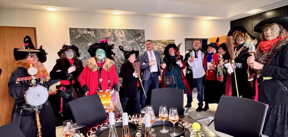 Die Alser Hexen im Rathaus neben Bürgermeister Steffen Jung, festlich verzierter Tisch mit Sekt und Luftschlangen