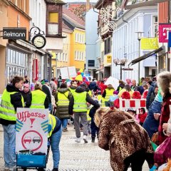 Fastnachtsumzug verkleidete Menschen die eine Staße entlang gehen und eine Kleine Polizei absperrung mit dem Hinweis das die Leute aufpassen sollen