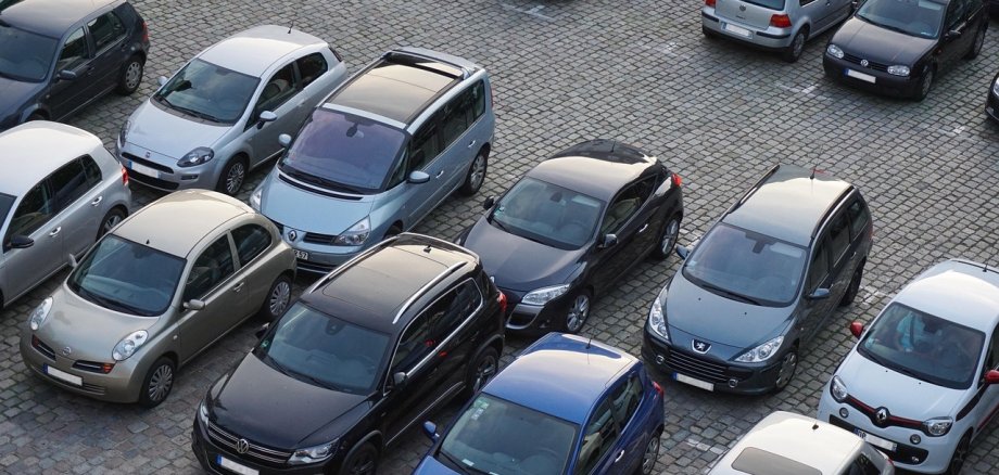 Man sieht einen Parkplatz mit geparkten Autos.