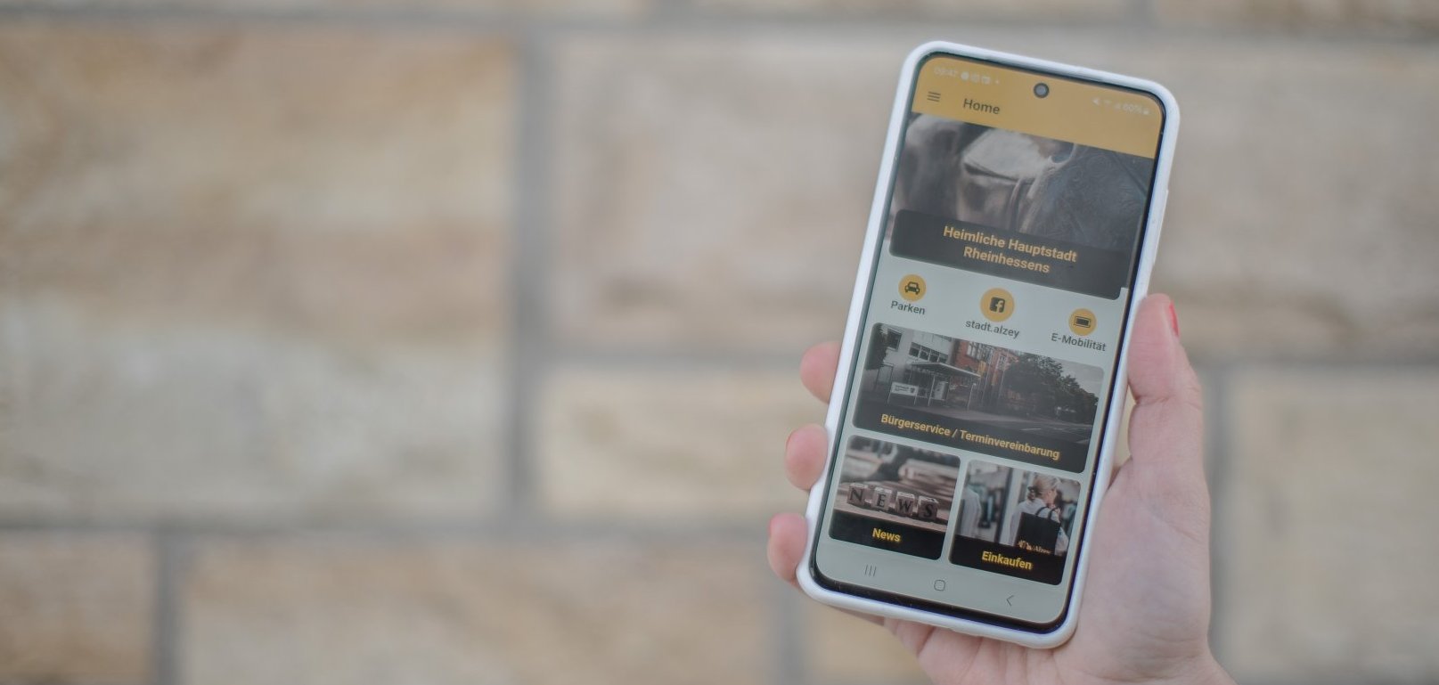 Werbung: Man sieht ein Handy mit geöfneter Alzey-App.