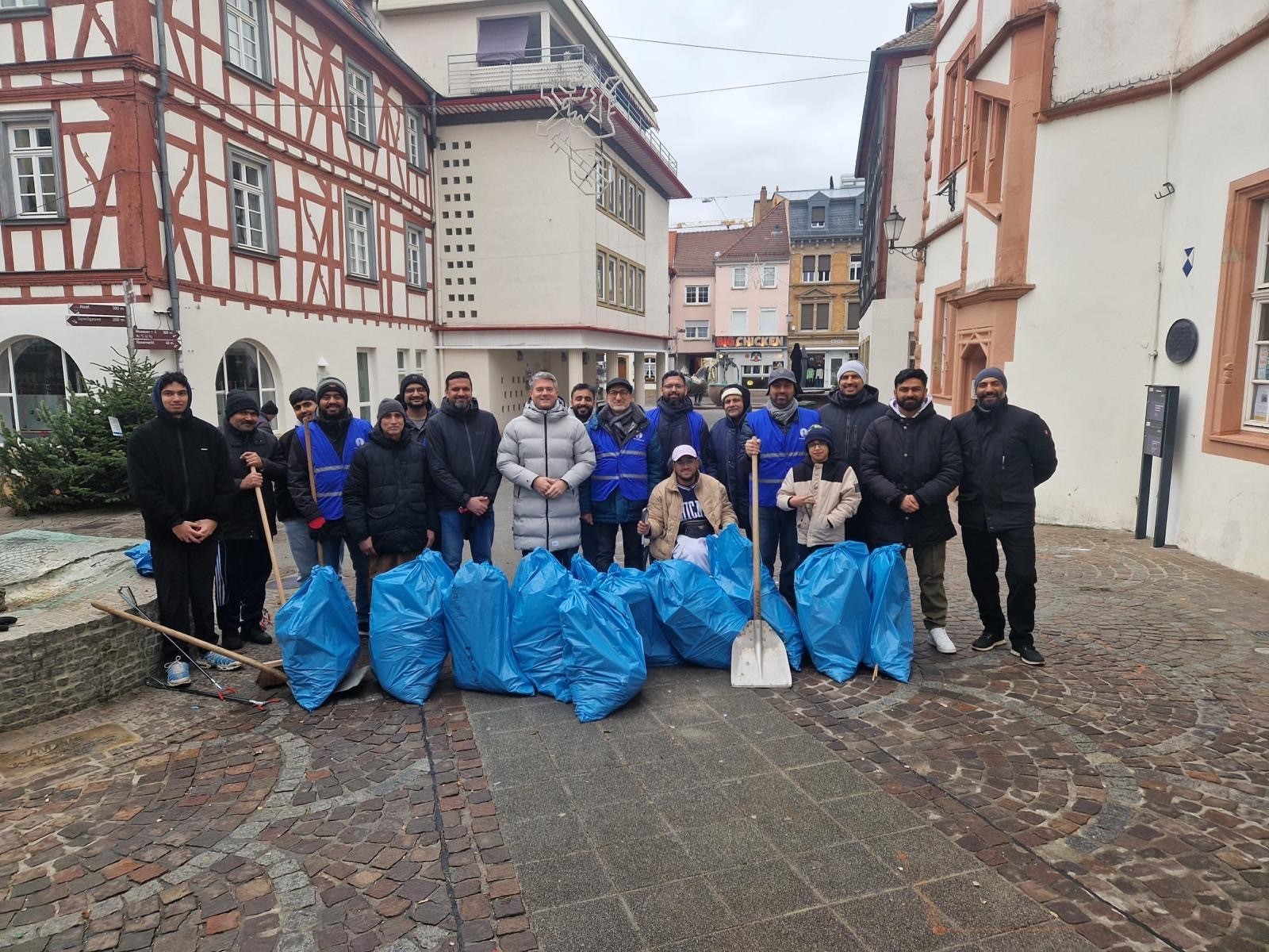 Rund 20 junge Muslime der Ahmadiyya-Gemeinde haben in einer ehrenamtlichen Aktion die Innenstadt von Alzey von Silvestermüll befreit. (Zu sehen sind die Menschen dieser Aktion sowie der Bürgermeister Steffen Jung und der Gesammelte Müll. Das Bild wurde auserdem am Fischmarkt gemacht vor dem "Alten Rathaus".)