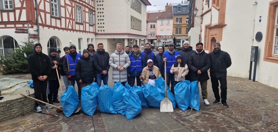 Rund 20 junge Muslime der Ahmadiyya-Gemeinde haben in einer ehrenamtlichen Aktion die Innenstadt von Alzey von Silvestermüll befreit. (Zu sehen sind die Menschen dieser Aktion sowie der Bürgermeister Steffen Jung und der Gesammelte Müll. Das Bild wurde auserdem am Fischmarkt gemacht vor dem "Alten Rathaus".)