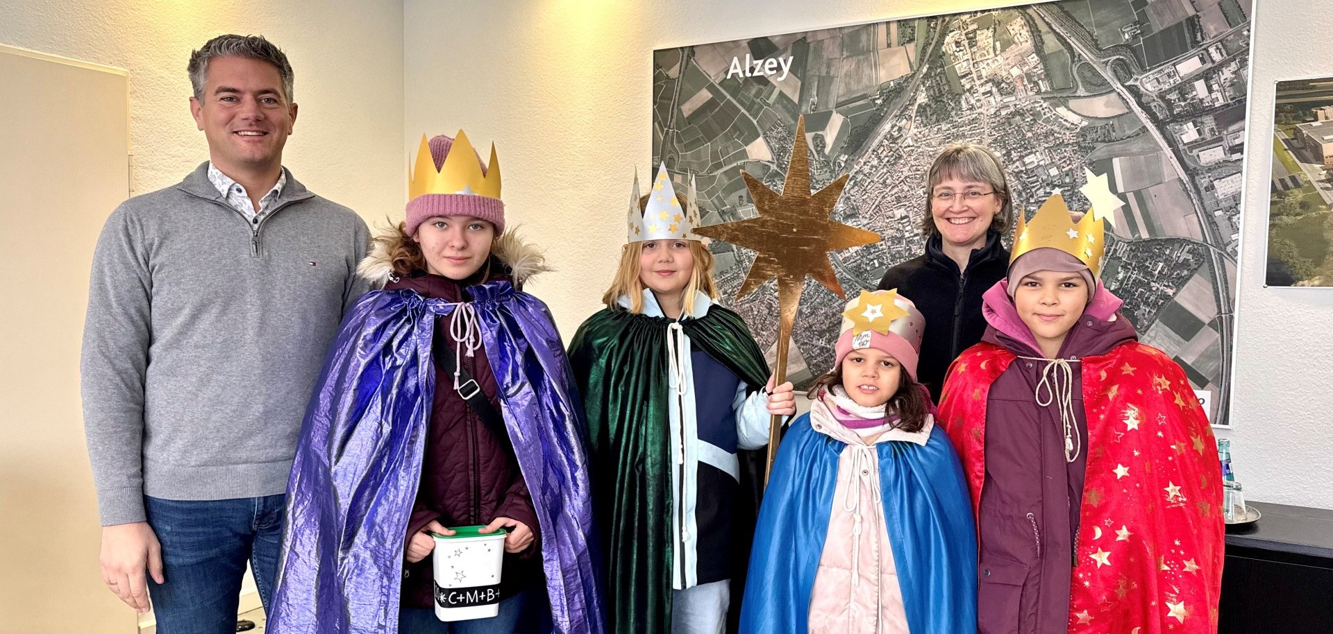 Das Bild Zeigt Bürgermeister Seffen Jung mit den Sternsingern 2026 vor der Alzeyer Stadt-Karte