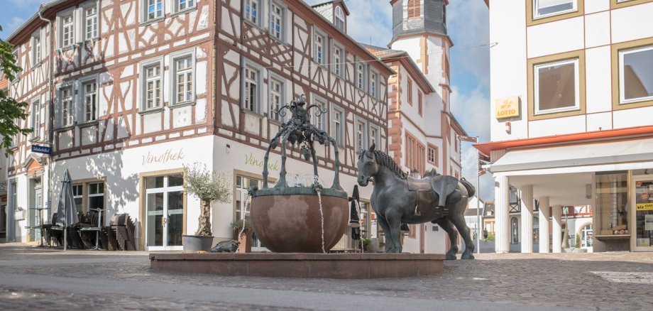 Ein Foto vom Rossmarkt, dem Brunnen, der Rossskulptur und der Vinothek.