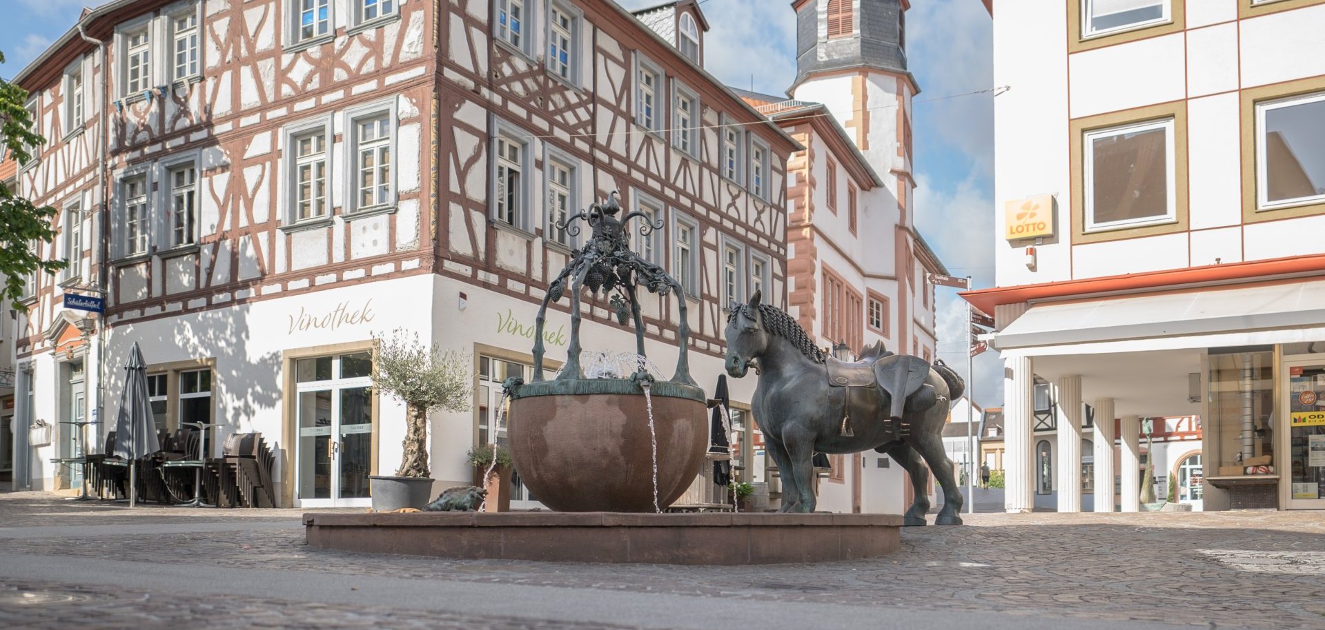 Ein Foto vom Rossmarkt, dem Brunnen, der Rossskulptur und der Vinothek.