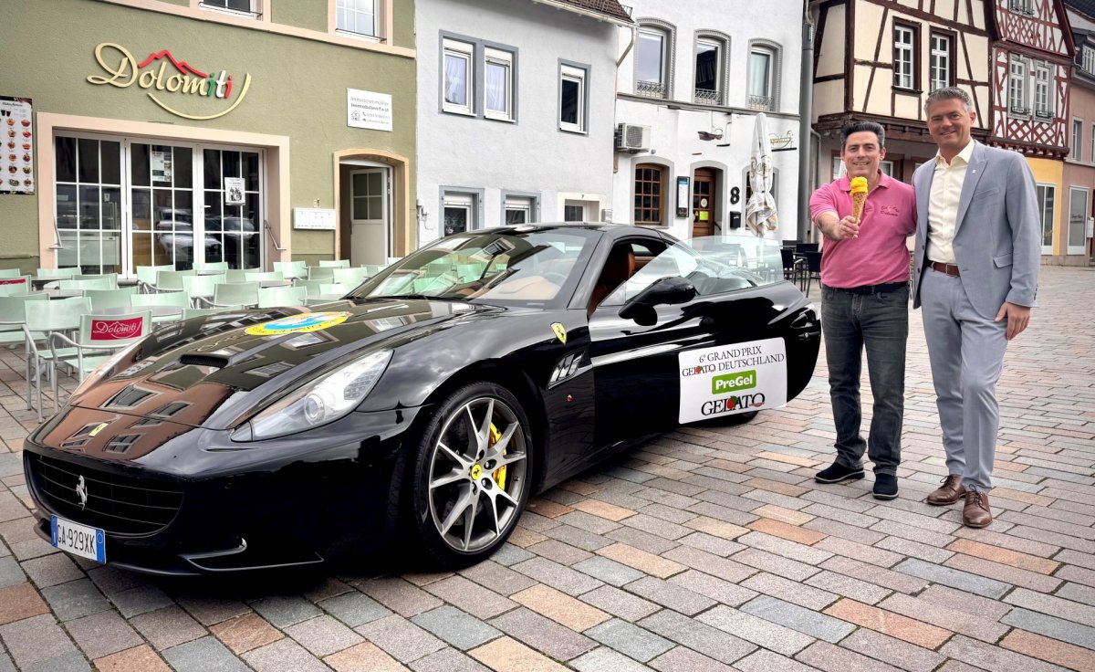 Bürgermeister Steffen Jung und Giuseppe der Besitzer des Eisladens mit seinem Mango-Eis und auch seinem gewonnenen Ferrari auf dem Grand Prix Gelato Deutschland steht.