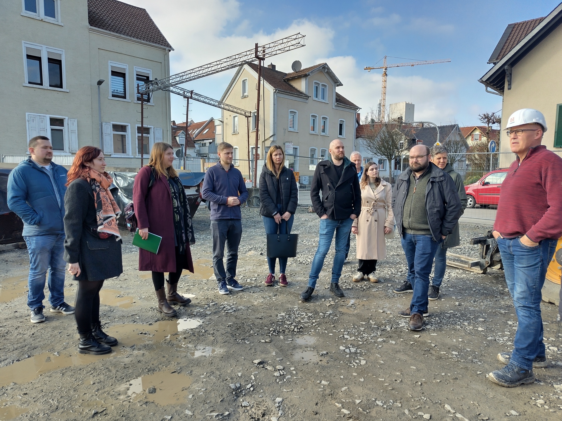 Man sieht Menschen die auf der Baustelle stehen und sich umsehen