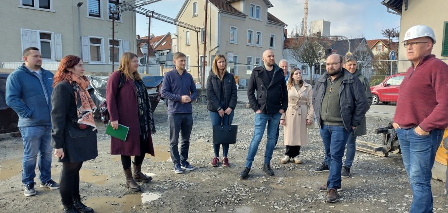 Man sieht Menschen die auf der Baustelle stehen und sich umsehen