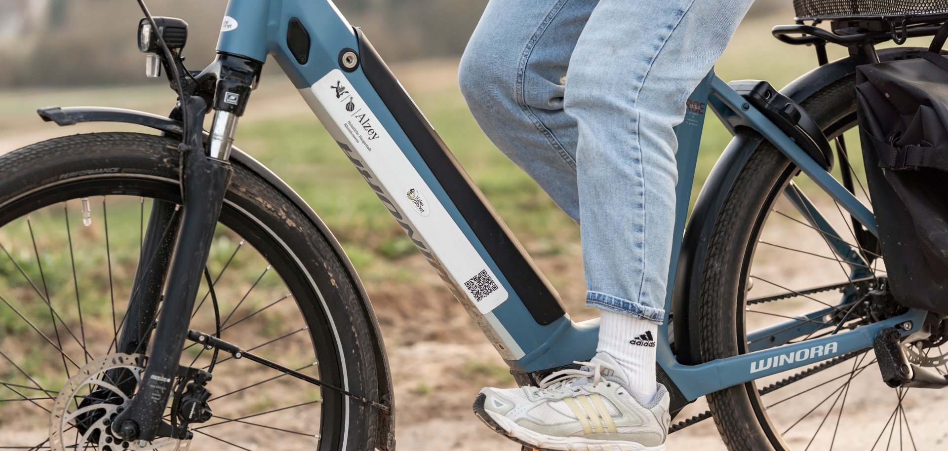abgebildet ist der untere Abschnitt eines Fahrradfahrers auf einem Fahrrad, der grade in dei Pedale tritt