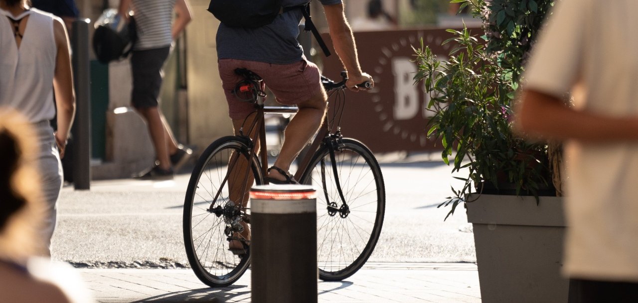 ein Fahrradfahrer wurde von hinten fotografiert, wie er grade durch eine Stadt fährt
