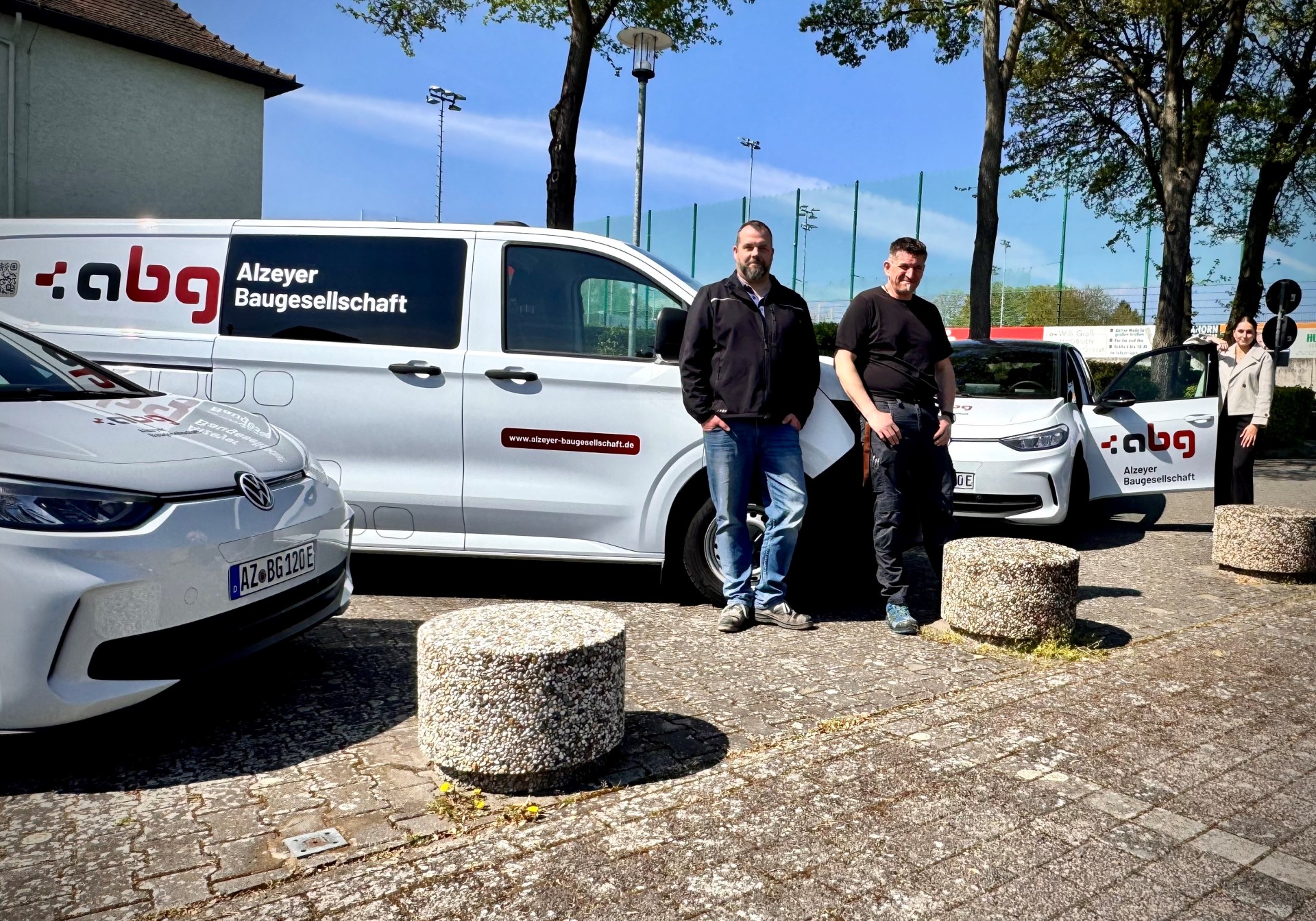 drei Personen stehen an jeweils drei verschiedenen Autos mit der Aufschrift abg angelehnt vor dem Wartbergbad