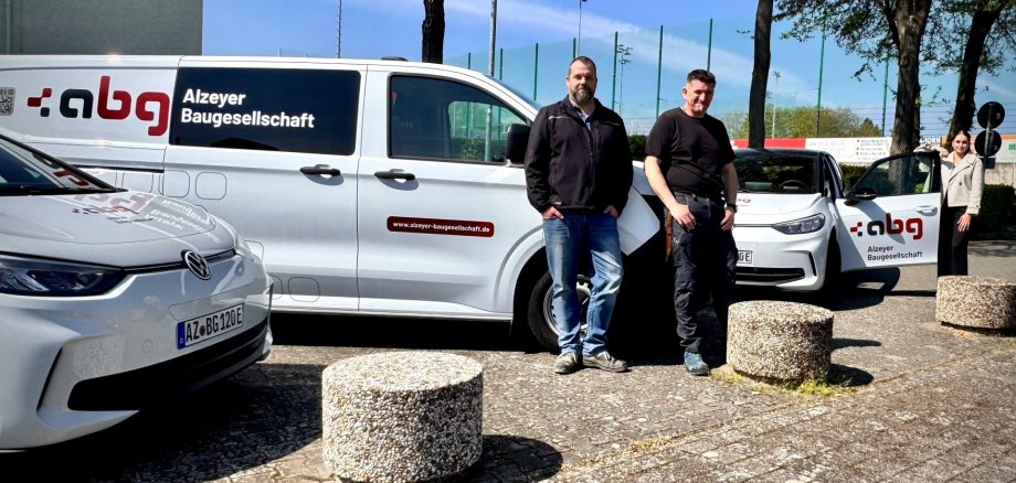 drei Personen stehen an jeweils drei verschiedenen Autos mit der Aufschrift abg angelehnt vor dem Wartbergbad