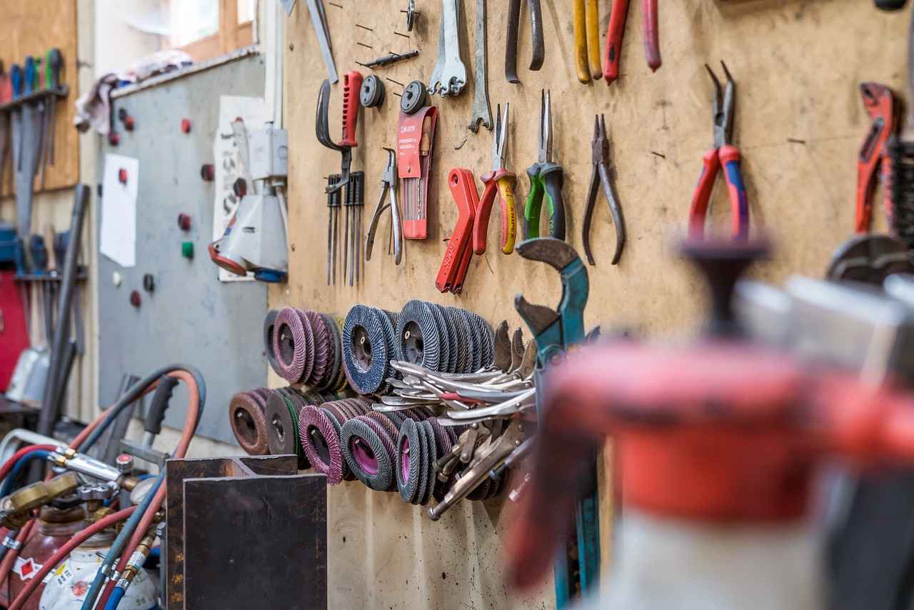 Man sieht eine Holzwand einer Werkstatt, an der viele verschiedene Werkzeuge hängen.