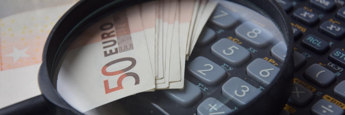 Geldscheine, Lupe und ein Taschenrechner