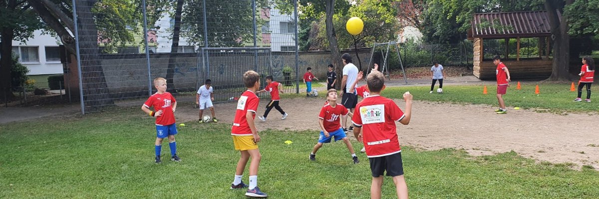 Mehrere Kinder spielen zusammen Fußball